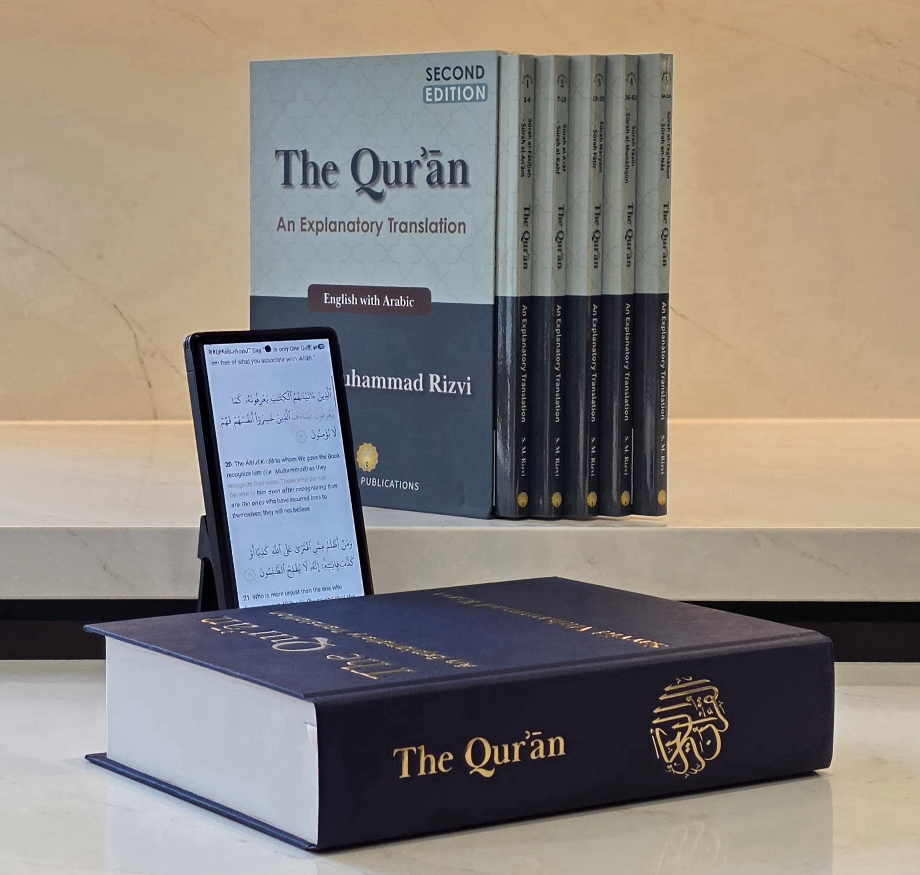 The Qur’ān 2nd Edition hardcover and 5-volume box set, with App 2.0 on a phone